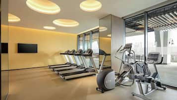 A modern gym with treadmills, elliptical machines, and a large mirror.