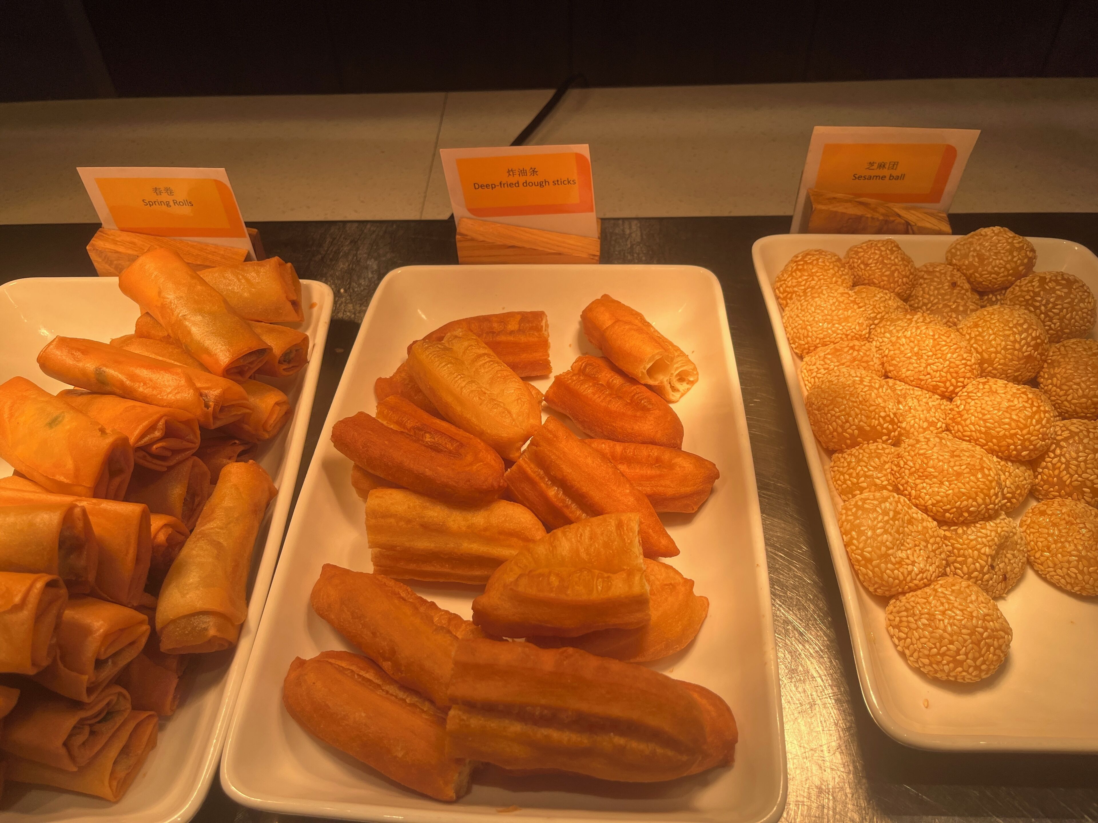 Three trays of food items: Spring Rolls, Deep-fried dough sticks, and Sesame balls.