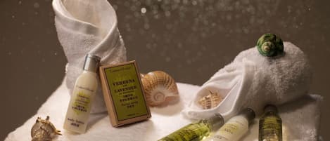 A towel with various spa products including a bottle of Verbena Lavender body lotion and a box of Verbena Lavender facial soap.