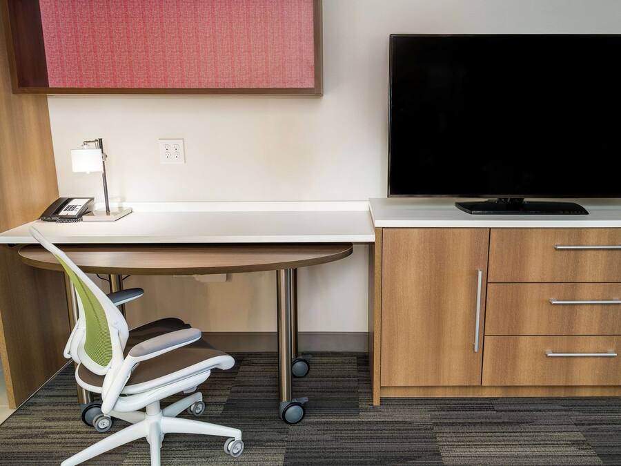 Un espacio de oficina moderno con un escritorio, una silla, un televisor y armarios de madera.