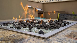 A fire feature with a grill and glass surround on an outdoor patio.