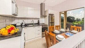 A modern kitchen with white cabinets, a stainless steel range hood, and a dining area with a table set for four.