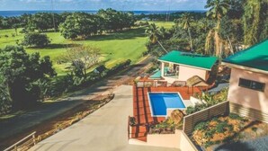 A house with a swimming pool, a tennis court, and a view of the ocean.