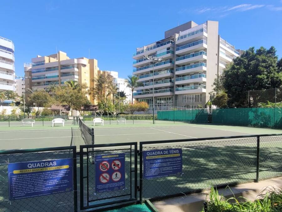 An outdoor tennis court surrounded by buildings, with signs indicating usage rules.