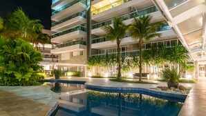 Un hotel moderno con piscina, rodeado de exuberante vegetación y palmeras.