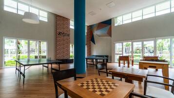 A spacious indoor area with multiple tables and chairs, a ping pong table, and a foosball table.