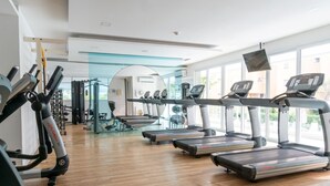 Un gimnasio con cintas de correr, máquinas de pesas y un espejo grande.