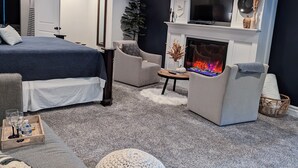 A modern living room with a fireplace, a large bed, and a television. - The Barn at Strasburg B&B (Strasburg)
