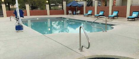 A swimming pool with lounge chairs and a hot tub area.