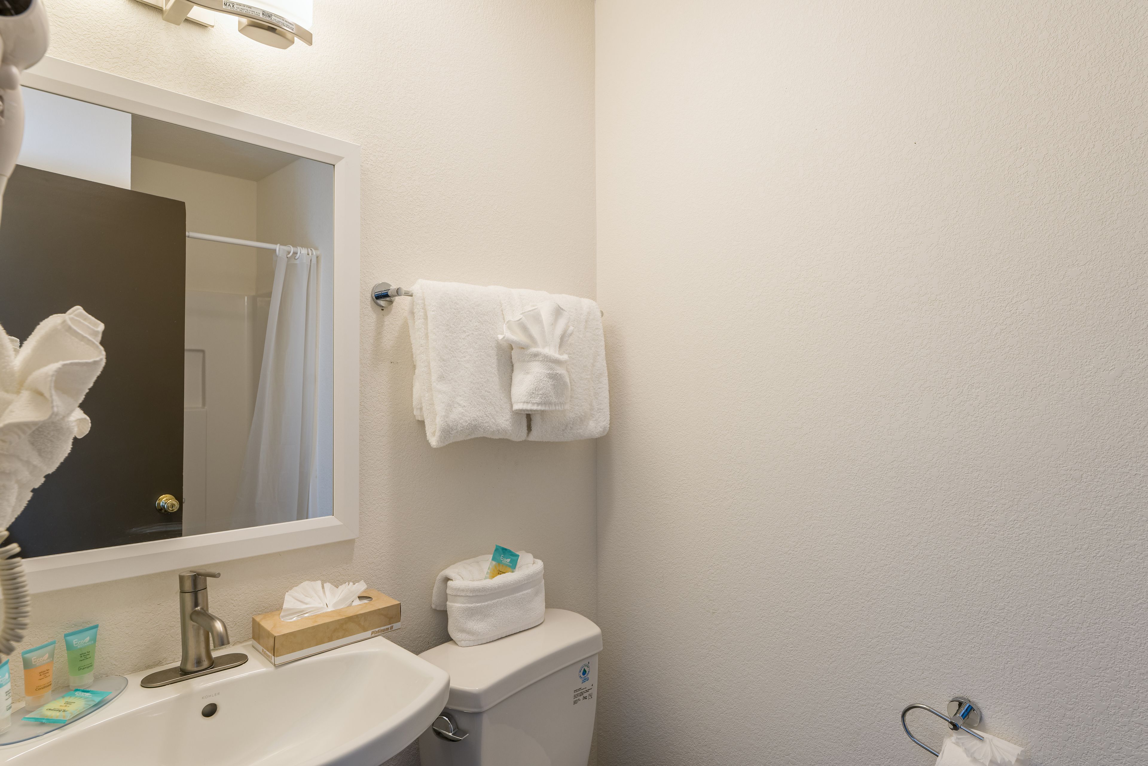 A bathroom with a sink, mirror, towel rack, and toiletries.