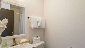 A bathroom with a sink, mirror, towel rack, and toiletries.