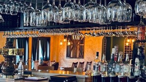 A bar area with multiple hanging wine glasses, a bar counter, and various bottles of alcohol. - Lux Verde Hotel (Cottonwood)