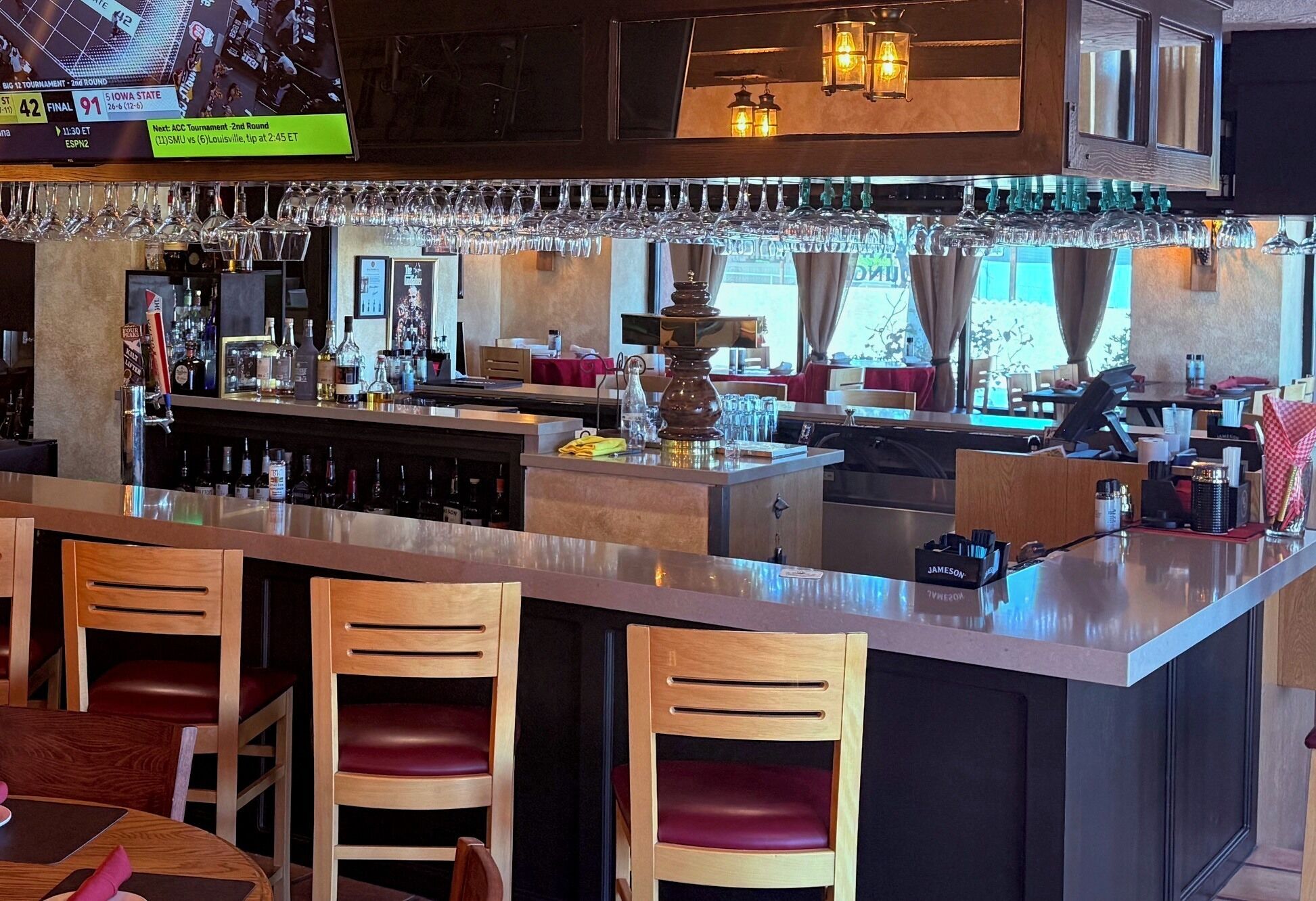 A bar area with a long counter, multiple stools, and a