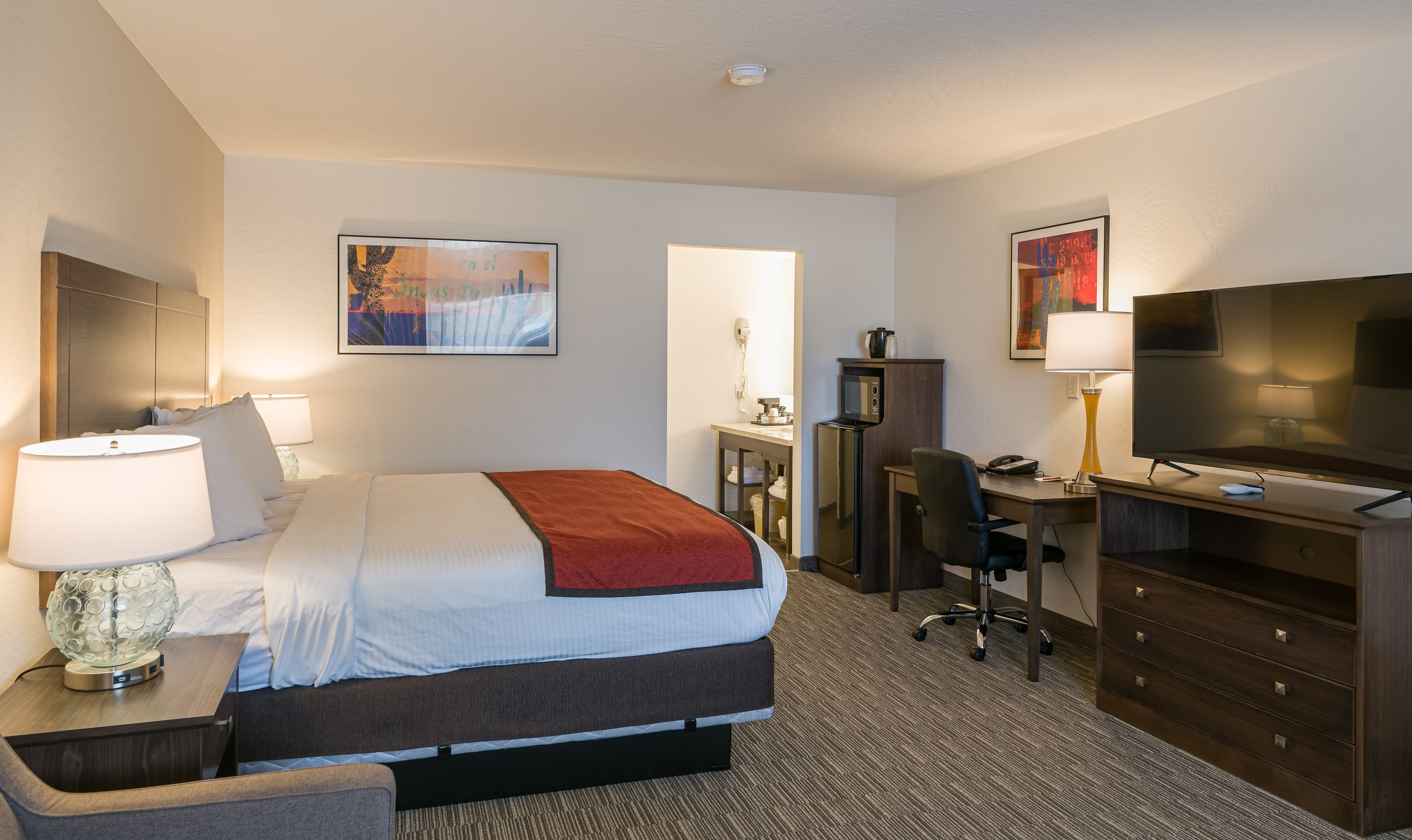 Une chambre d’hôtel équipée d’un lit, d’un bureau, d’une télévision et d’un miroir.