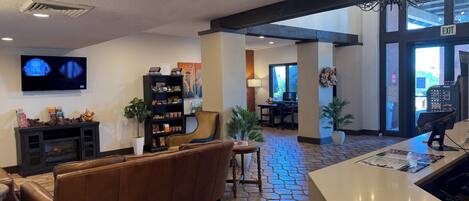 A lobby with a fireplace, a television, a bookshelf, a sofa, and a reception desk.