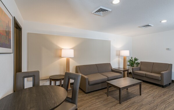 Un salon moderne comprenant un canapé, des fauteuils, une table basse et deux lampes.