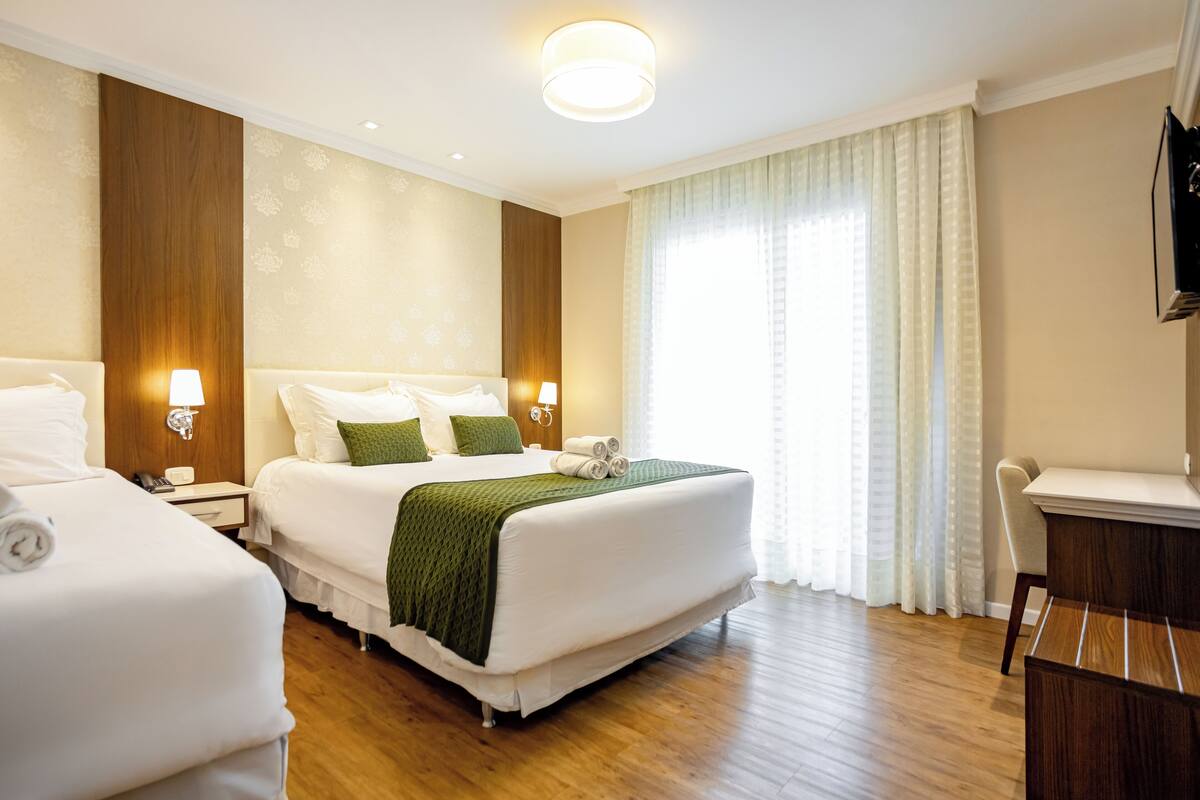 A hotel room with two beds, a desk, and a TV.