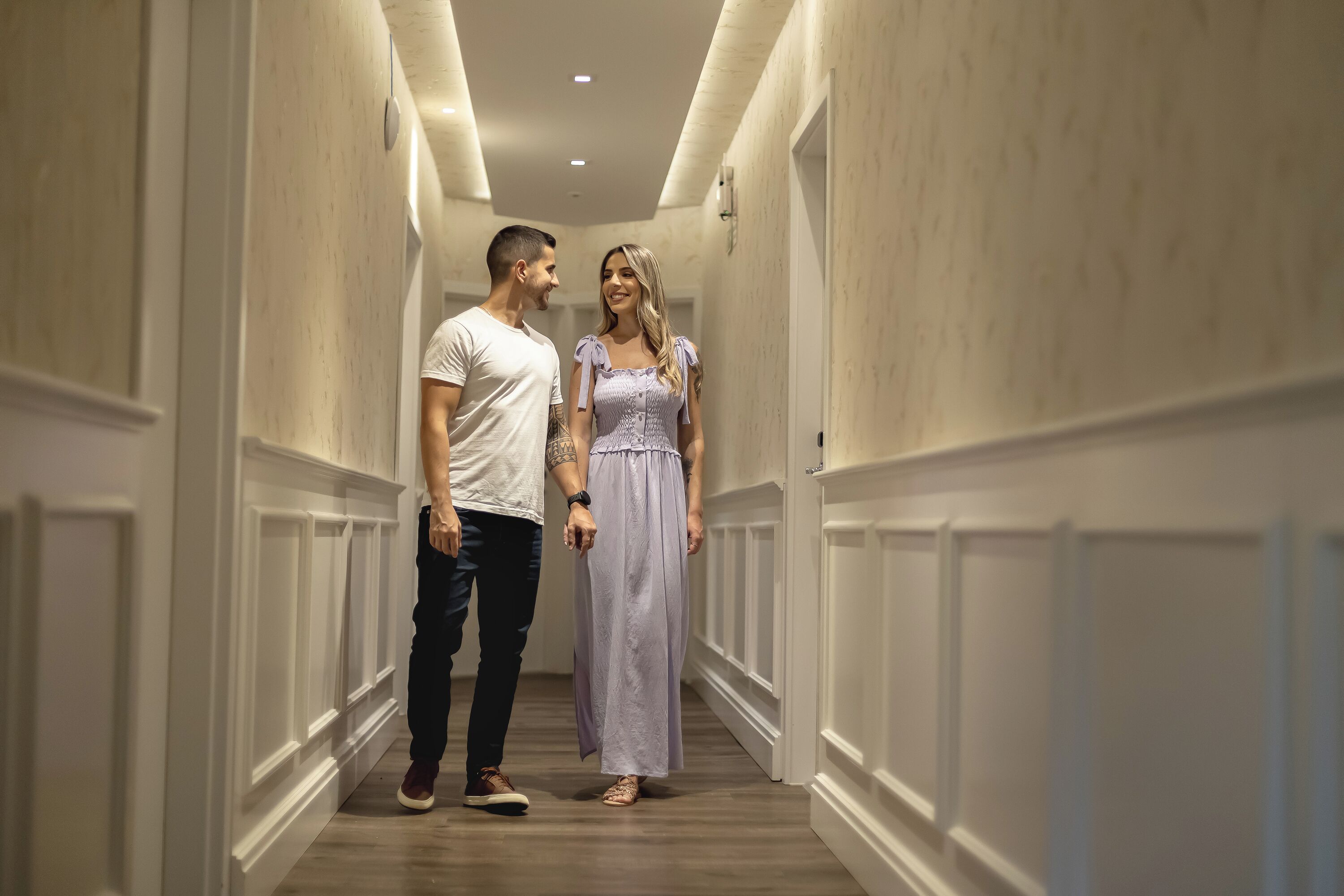 A hallway with white wainscoting and a wooden floor.