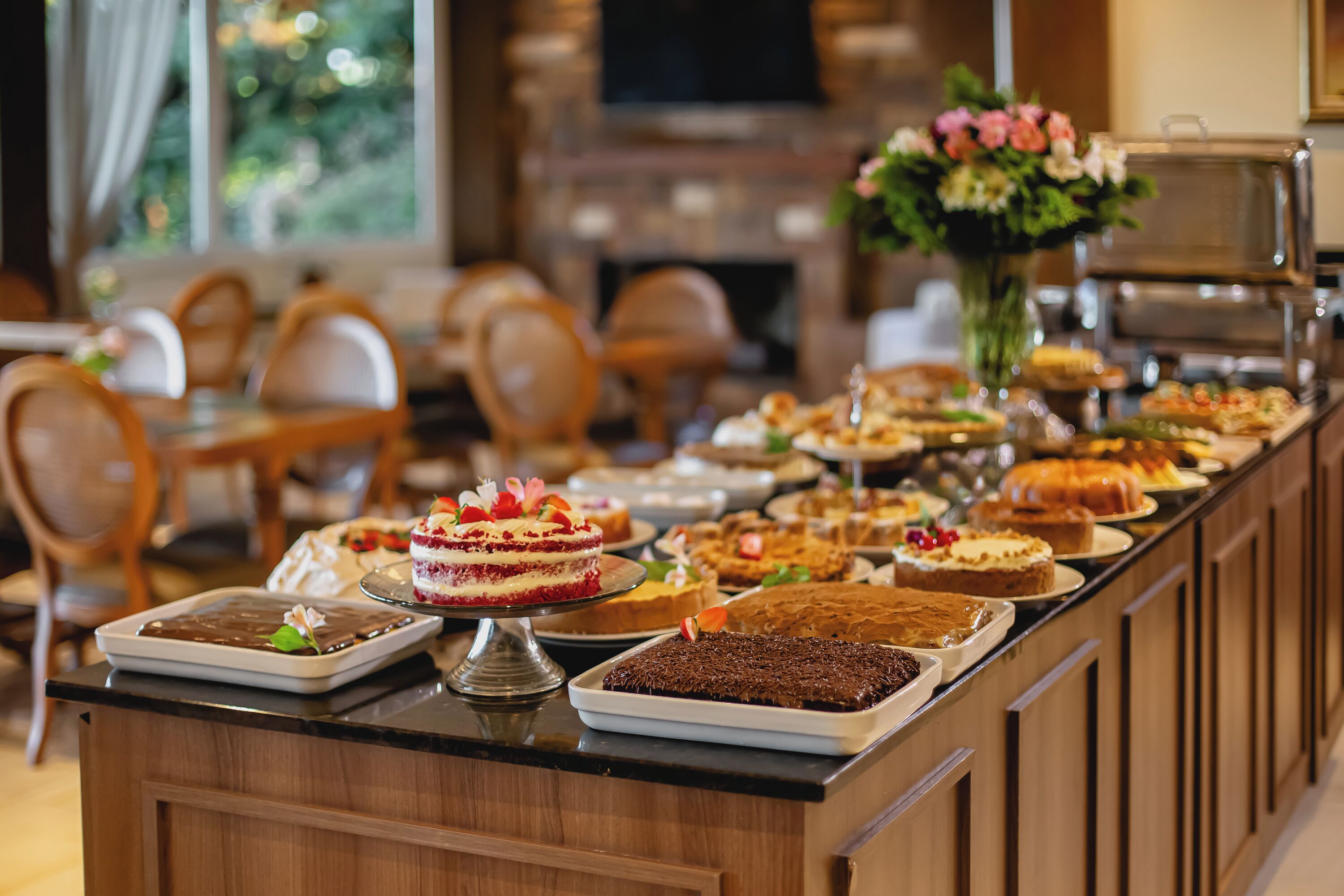 A buffet with various desserts and a floral centerpiece.