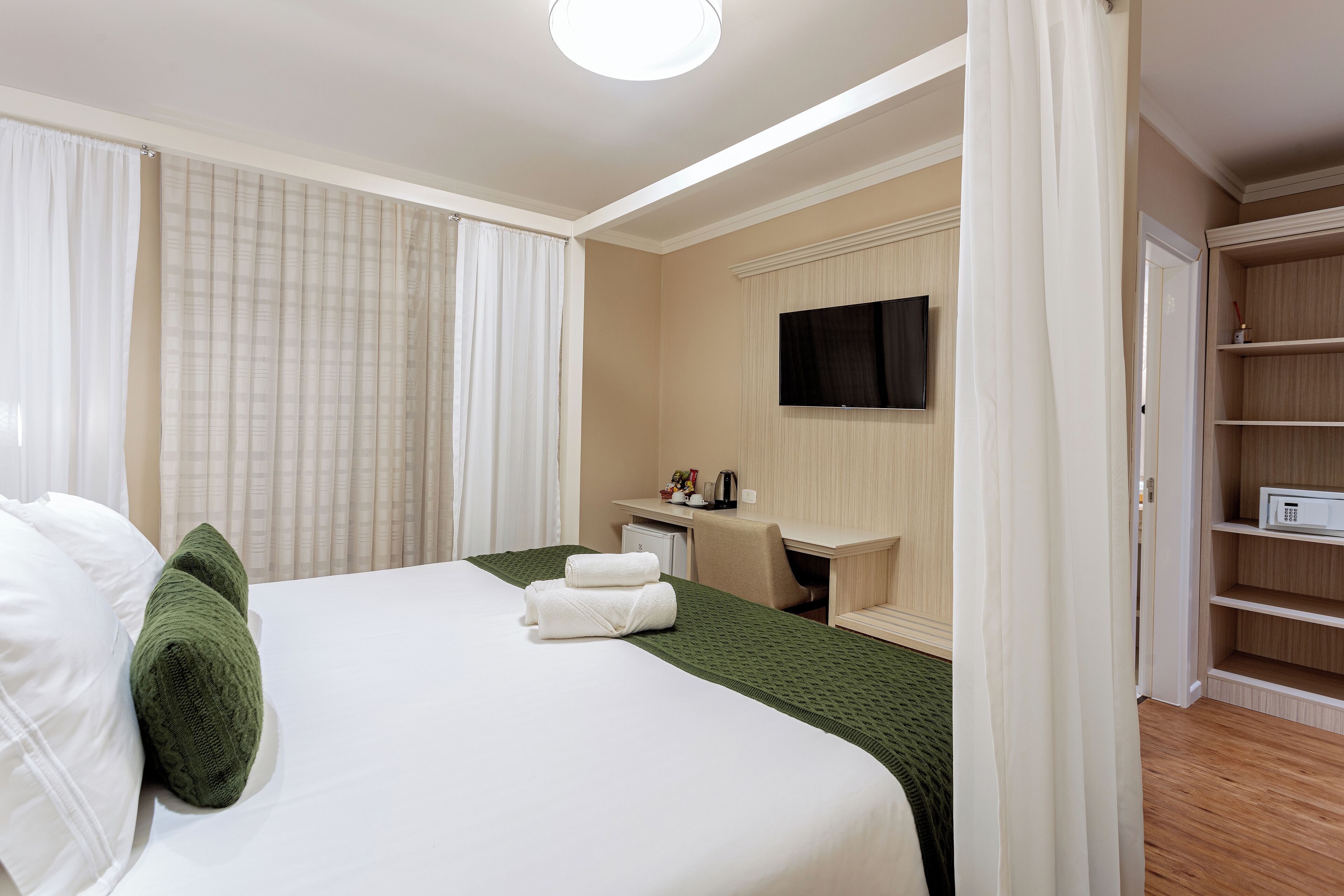 Ein Hotelzimmer mit einem Bett, einem Schreibtisch, einem Fernseher und einem Kleiderschrank.