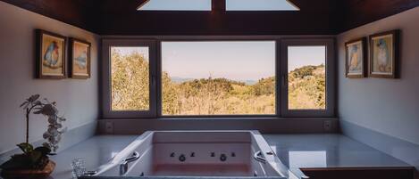 Un baño moderno con un ventanal grande, una bañera y obras de arte enmarcadas.