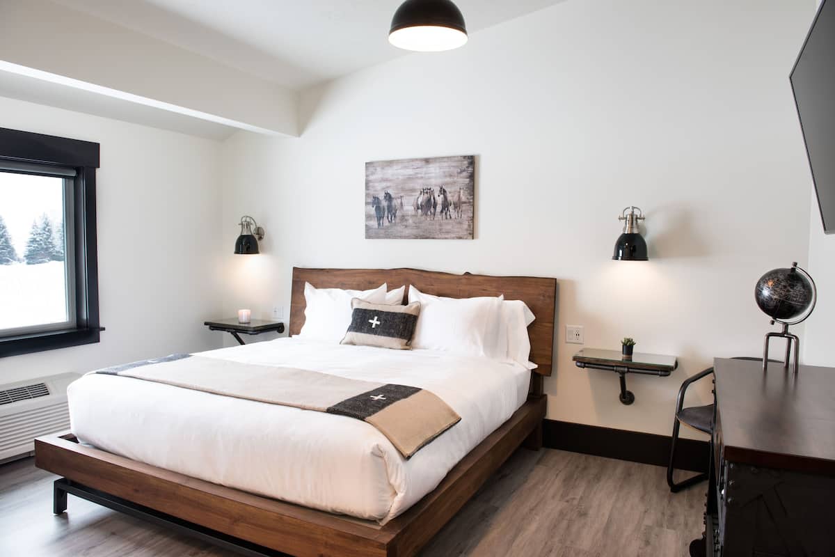 A modern bedroom with a wooden bed, a desk, and a globe.