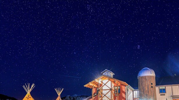 A building with a large tower and two illuminated teepees in front. - Compass Rose Lodge (Huntsville)