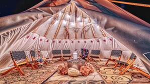 A large, well-lit tent with a central fire pit and multiple seating areas. - Compass Rose Lodge (Huntsville)