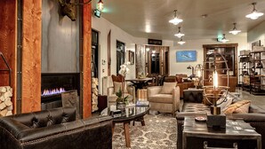 A cozy living room with leather sofas, a fireplace, and a dining area with a large table. - Compass Rose Lodge (Huntsville)