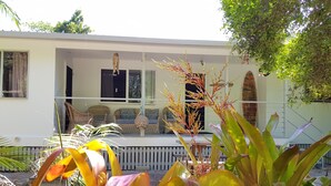 Une maison avec une véranda, des meubles en osier et des plantes tropicales.