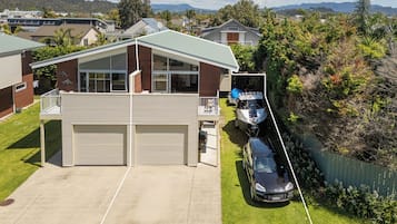 Une maison à deux étages avec un garage, un balcon et une voiture garée dans l’allée.