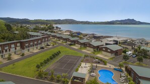 A residential area with houses, a tennis court, and a swimming pool. - Ocean Serenity Apartments Whitianga (Whitianga)