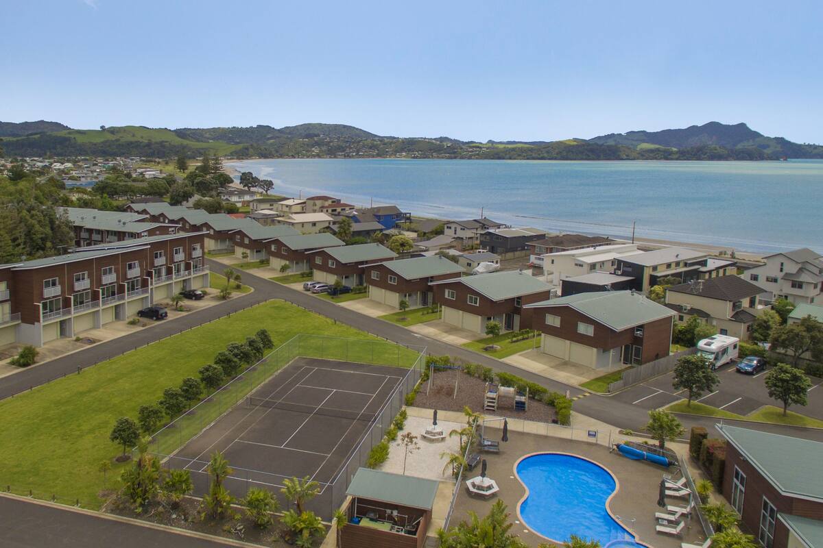 Un quartier résidentiel avec des maisons, un court de tennis et une piscine.