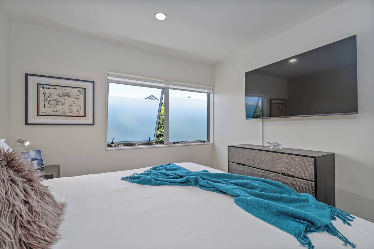 Une chambre à coucher avec un lit, une fenêtre donnant sur un beau paysage, une commode et une carte encadrée accrochée au mur.