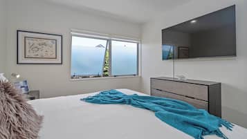 Une chambre à coucher avec un lit, une fenêtre donnant sur un beau paysage, une commode et une carte encadrée accrochée au mur.