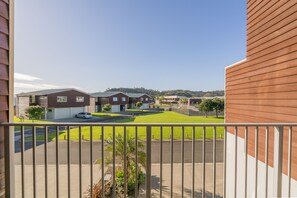 A residential area with houses, a clear sky, and a balcony with a railing.