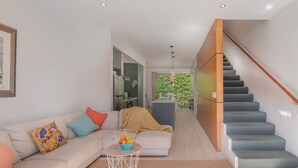 A modern living room with a sofa, coffee table, and a staircase leading to an upper level.