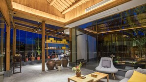 A modern interior with a wooden ceiling, large windows, and a seating area with a sofa and armchair. - Old Street Moye Inn (Huangshan)