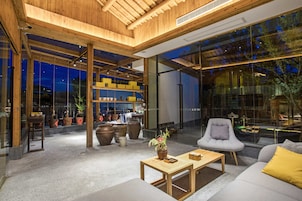 A modern interior with a wooden ceiling, large windows, and a seating area with a sofa and armchair.