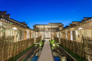 A traditional courtyard with a central water feature, surrounded by buildings with classic architecture.