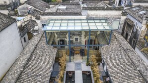 A traditional building with a modern glass extension, featuring a courtyard with seating and plants. - Old Street Moye Inn (Huangshan)