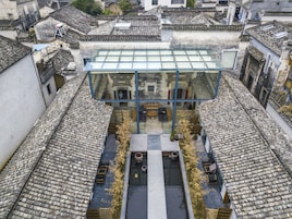 A traditional building with a modern glass extension, featuring a courtyard with seating and plants.
