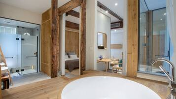 Ein modernes Badezimmer mit einer großen Badewanne, Holzbalken und einer Duschkabine aus Glas.