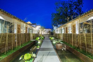 A traditional courtyard with a central pathway, bamboo fences, and water features.