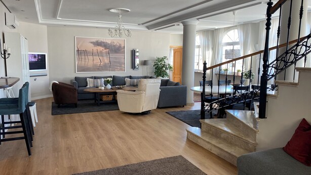 A spacious living area with a sofa, coffee table, and a staircase with a black railing. - Penthouse Duplex, Fuengirola (Los Pacos) (Fuengirola)