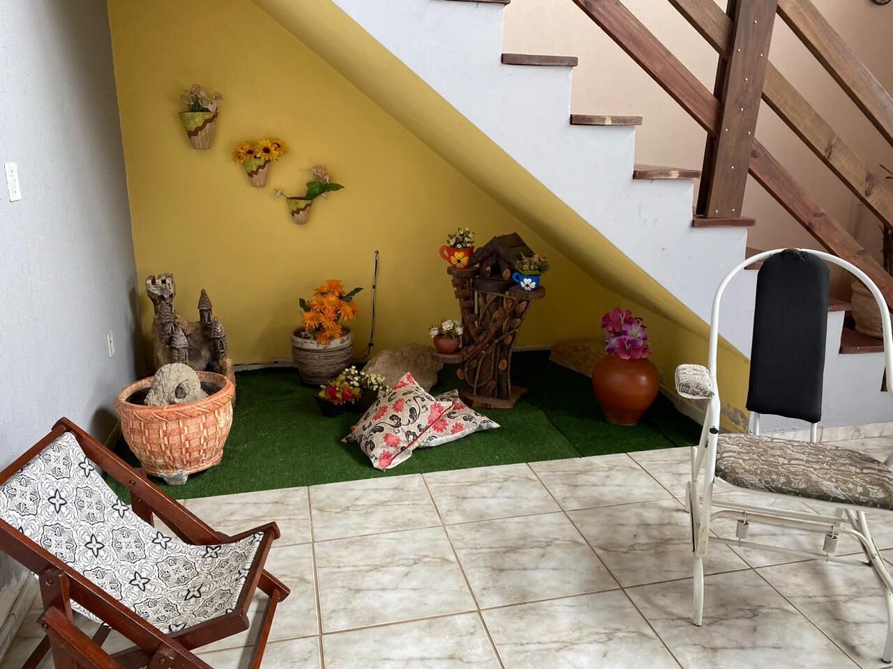 A staircase with a yellow wall, a wooden chair, a white chair, and various decorative items including a basket, a wooden structure, and a vase.