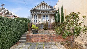 A two-story house with a balcony, a brick staircase, and a metal fence.