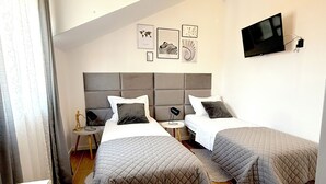 A hotel room with two beds, a flat-screen TV mounted on the wall, and artwork on the wall. - Marjan Hill Apartment - close to center & own garage (Split)
