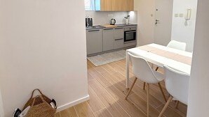 A modern kitchen with wooden cabinets, a dining table with chairs, and a hanging light fixture. - Marjan Hill Apartment - close to center & own garage (Split)