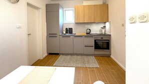 A compact kitchen with grey cabinets, a built-in oven, a sink, and a window above the countertop. - Marjan Hill Apartment - close to center & own garage (Split)